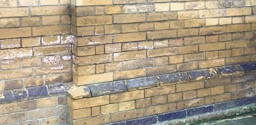 Mur de façade en briques jaunes humide à cause des remontées capillaires